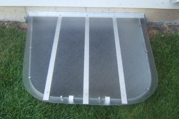 Clear window well cover on a galvanized extension well against a brick home